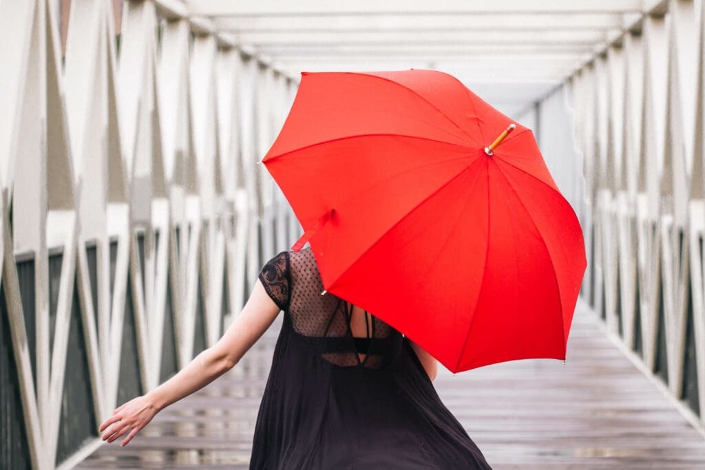 girl on a bridge with a red umbrella