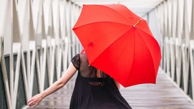 girl on a bridge with a red umbrella