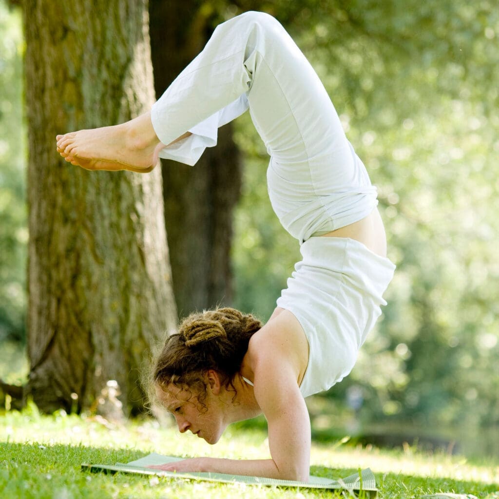 Person in white doing a forearm stand. 