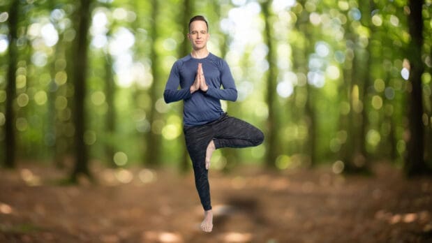 James Donegan practicing tree pose in a forest